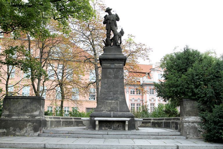 Na pražském Karlově náměstí stojí pomník cestovatele dobrodruha, který na cestách za květinami přišel o ruku.