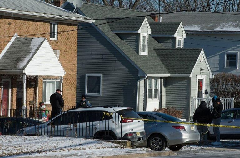 Policie na verandě domu v Long Branch, kde byla na Silvestra rodina zmasakrována.