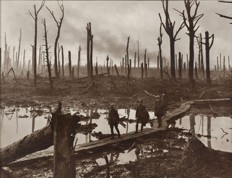Australští vojáci na dřevěné lávce přes bažinu v lesíku ve Flandrech. FOTO: Frank Hurley, Public domain, via Wikimedia Commons