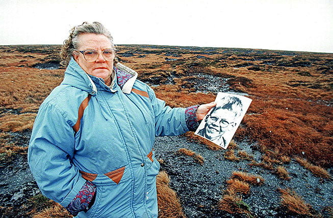 Winifred Johnsonová, matka pohřešovaného chlapce Keitha Bennetta, na snímku na Saddleworth Moor, s fotografií svého syna, 25. ledna 1995. Foto: Parrot of Doom CC BY-SA 3.0 