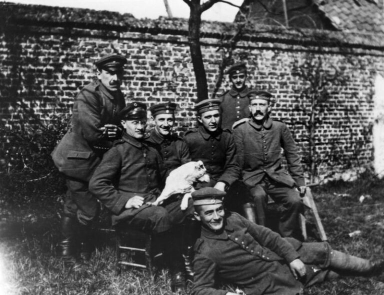 Když vojín Adolf Hitler (sedící vpravo) dostane rozkaz oholit knír, nese to velmi těžce. (Bundesarchiv, Bild 146-1974-082-44 / CC-BY-SA 3.0, CC BY-SA 3.0 de, commons.wikimedia)